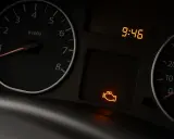 Cruscotto auto con spia motore rossa accesa ma la macchina va bene. L'ora segna 9:46.