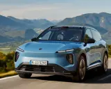 NIO ES6 blu sfreccia su una strada panoramica tra montagne verdi.
