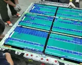 Un tecnico lavora su un pacco batteria, con celle verdi e blu che ricordano una blade battery.