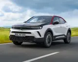 Opel Mokka bianco e nero con tetto rosso, su strada panoramica. Nonostante il design accattivante, alcuni utenti segnalano opel mokka difetti.
