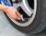Mano che collega un tubo blu alla valvola per gonfiare gomme auto.