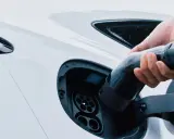 Mano inserisce la spina per trasformare l'auto in elettrica. Ricarica di un veicolo a zero emissioni.