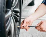 Mani che gonfiano uno pneumatico. Evitare pneumatici troppo gonfi conseguenze: usura irregolare e minore aderenza.