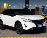 Nissan Qashqai e-POWER: potenza e autonomia per 360 km. L'auto è bianca, con tetto nero, e si trova vicino a una colonnina di ricarica.