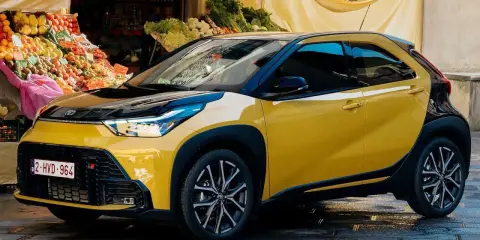 Toyota Aygo X gialla parcheggiata davanti a un mercato. Nessun problema visibile, solo un'auto elegante.