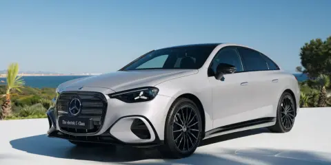 La Mercedes Classe C 2026, un'elegante berlina elettrica, si presenta con un design moderno e sportivo, con cerchi neri e uno sfondo marino.