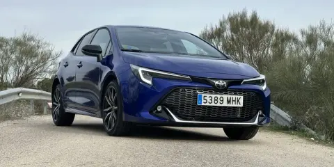 Toyota Corolla blu parcheggiata su strada sterrata, con vegetazione sullo sfondo. Un'auto che offre diverse motorizzazioni.