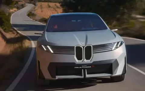 La BMW Neue Klasse X sfreccia su una strada tortuosa, un'icona di design futuristico.