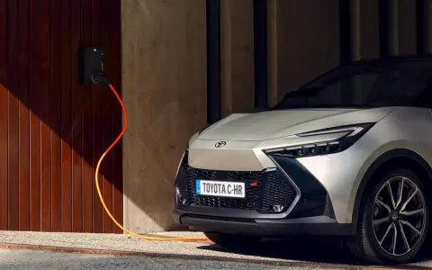 Toyota C-HR GR in argento, con cavo arancione collegato alla stazione di ricarica. L'auto plug-in è pronta per la sua prossima avventura.
