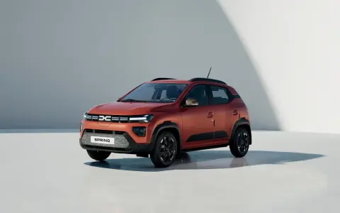 Dacia Spring, un'auto elettrica arancione, pronta per un viaggio in autostrada con la sua autonomia.