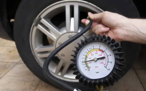 Controllo della pressione gomme auto con manometro. La lancetta indica un valore basso, suggerendo la necessità di gonfiare.