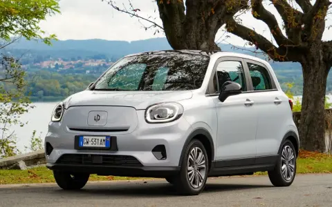 Leapmotor T03, un'auto elettrica grigia parcheggiata vicino a un lago, pronta per un viaggio con la sua eccellente autonomia.
