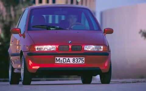 La BMW E1 rossa, un prototipo elettrico, si presenta con un design compatto e futuristico, pronta a sfrecciare nel traffico urbano.