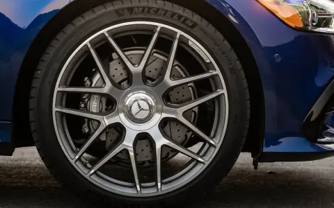 Ruota di un'auto blu con cerchi AMG e freni a disco forati. Il pneumatico Michelin mostra un leggero segno di usura.