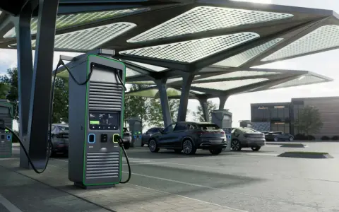 Moderne colonnine ricarica auto elettriche sotto una pensilina con pannelli solari. Diverse auto in carica.