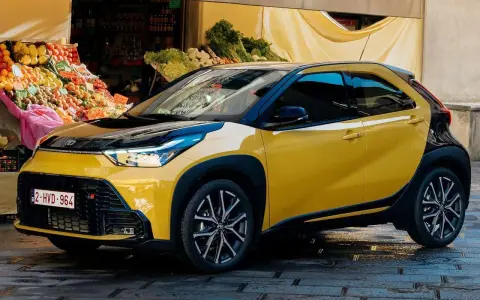 Toyota Aygo X gialla parcheggiata davanti a un mercato. Nessun problema visibile, solo un'auto elegante.