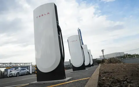 Stazione di ricarica Tesla Supercharger, con una Tesla in carica. Il costo del servizio è un fattore importante per i proprietari.
