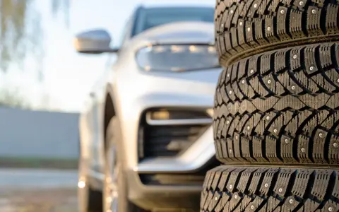 Gomme chiodate in primo piano, con un'auto bianca sfocata sullo sfondo. Mi chiedo se posso montare gomme con altezza diversa per affrontare ogni tipo di terreno.
