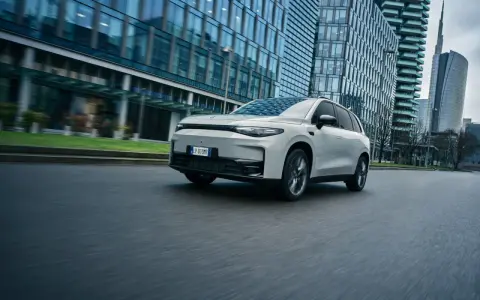 La Leapmotor C10 REEV sfreccia su strada, circondata da moderni grattacieli.