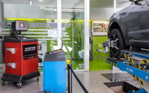 Attrezzatura per la convergenza auto in officina. Un'auto è sollevata su un ponte, con sensori applicati alla ruota.