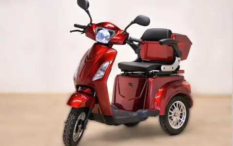Un'auto elettrica a 3 ruote, rossa metallizzata, con sedile comodo e bauletto posteriore. Ideale per muoversi in città con stile e praticità.