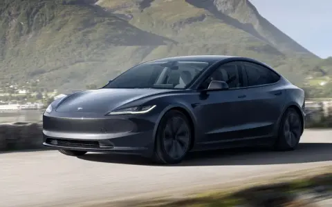 Tesla Model 3 grigia in movimento su strada panoramica, un'opzione tesla economica per esplorare la natura.