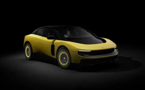 Un'audace Ferrari F244 gialla con tetto nero e cerchi dorati, illuminata da un fascio di luce su sfondo scuro.