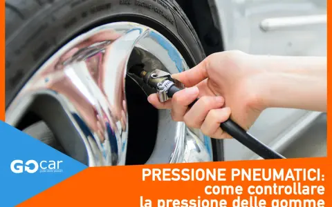 Controllo gomme auto: una mano collega il tubo di un compressore alla valvola di un pneumatico cromato. Essenziale per la sicurezza.