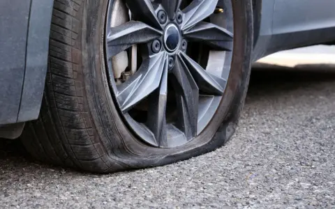 Gomma bucata dell'auto, sgonfia e appoggiata sull'asfalto. Un inconveniente che ferma ogni viaggio.