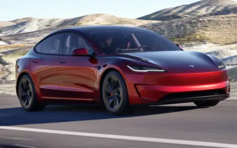 Tesla Model 3 rossa su strada panoramica. Il suo peso è ottimizzato per prestazioni elettriche.