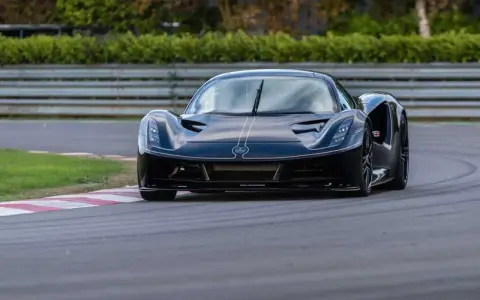 La Lotus Evija nera sfreccia su una pista, con un'aria di potenza e velocità.