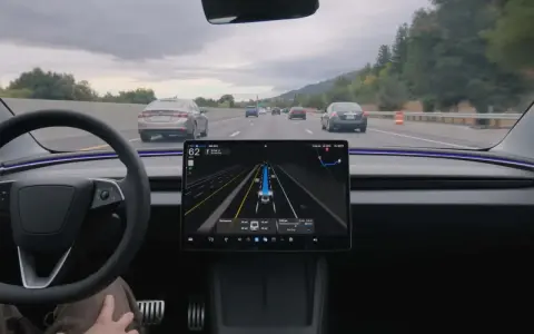 Interno di una Tesla con il sistema FSD attivo, mostra la guida autonoma in autostrada con visualizzazione delle auto circostanti.