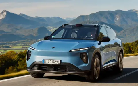 NIO ES6 blu sfreccia su una strada panoramica tra montagne verdi.