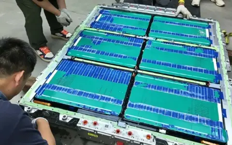 Un tecnico lavora su un pacco batteria, con celle verdi e blu che ricordano una blade battery.