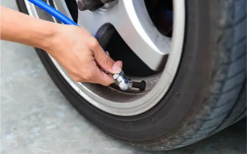 Mano che collega un tubo blu alla valvola per gonfiare gomme auto.