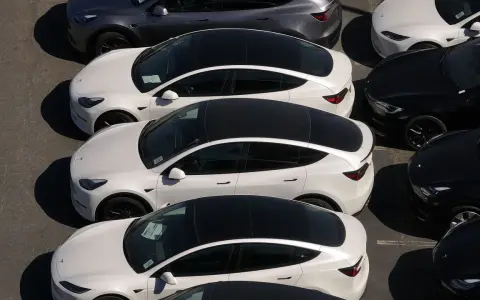 Parcheggio di auto elettriche in Italia, con modelli bianchi e grigi in fila, pronti per la consegna.