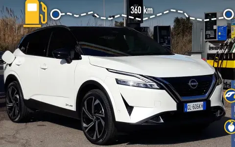 Nissan Qashqai e-POWER: potenza e autonomia per 360 km. L'auto è bianca, con tetto nero, e si trova vicino a una colonnina di ricarica.