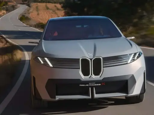La BMW Neue Klasse X sfreccia su una strada tortuosa, un'icona di design futuristico.