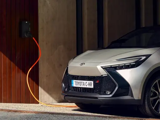 Toyota C-HR GR in argento, con cavo arancione collegato alla stazione di ricarica. L'auto plug-in è pronta per la sua prossima avventura.