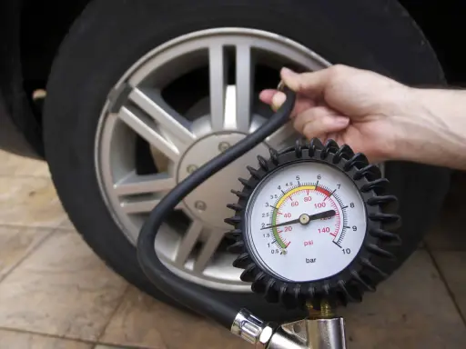 Controllo della pressione gomme auto con manometro. La lancetta indica un valore basso, suggerendo la necessità di gonfiare.