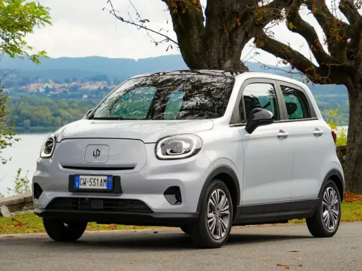 Leapmotor T03, un'auto elettrica grigia parcheggiata vicino a un lago, pronta per un viaggio con la sua eccellente autonomia.