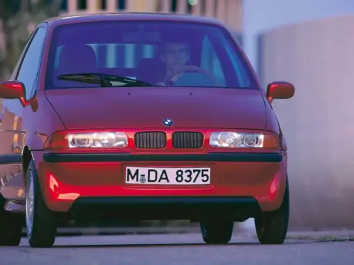 La BMW E1 rossa, un prototipo elettrico, si presenta con un design compatto e futuristico, pronta a sfrecciare nel traffico urbano.