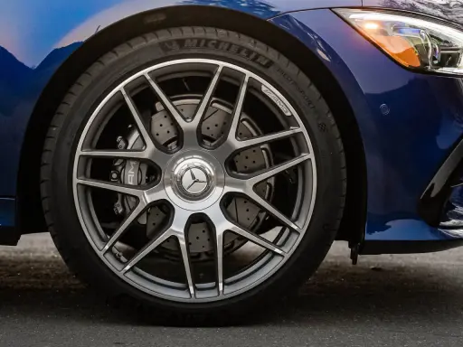 Ruota di un'auto blu con cerchi AMG e freni a disco forati. Il pneumatico Michelin mostra un leggero segno di usura.