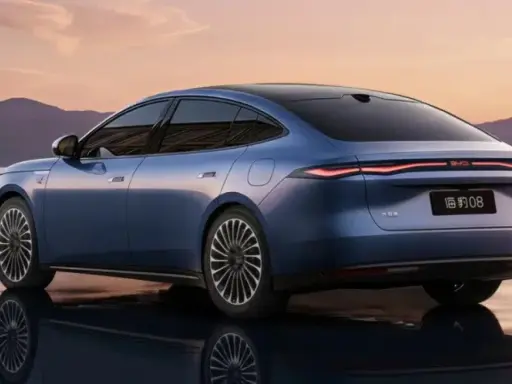 BYD Seal 08, berlina blu elettrica, riflette sull'acqua al tramonto, con montagne sullo sfondo.