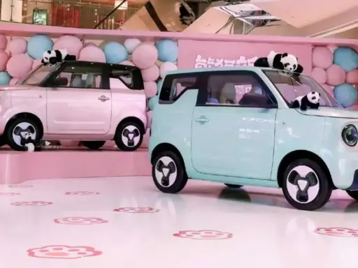 Due Geely Panda rosa e azzurra, circondate da palloncini e peluche di panda, in un allestimento a tema.