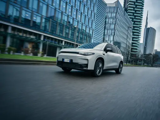 La Leapmotor C10 REEV sfreccia su strada, circondata da moderni grattacieli.