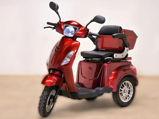 Un'auto elettrica a 3 ruote, rossa metallizzata, con sedile comodo e bauletto posteriore. Ideale per muoversi in città con stile e praticità.