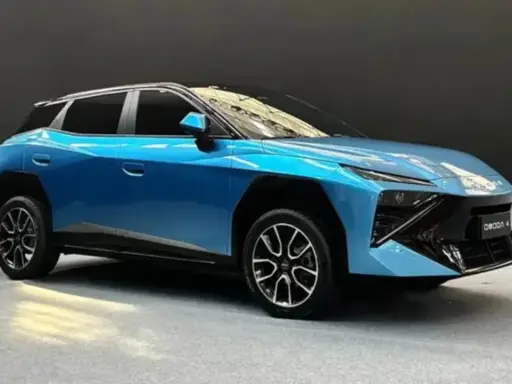 Un'elegante Omoda 4 blu metallizzato, con un design futuristico e cerchi in lega sportivi, si presenta su un pavimento grigio.