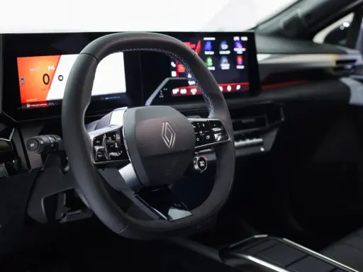 Volante e cruscotto digitale con schermi moderni, dettagli blu e logo Renault. Interni della nuova Clio 2026.