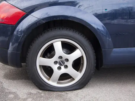 Ruota posteriore di un'auto blu con evidente perdita pressione pneumatici. Il coprimozzo riporta il logo "Borbet".